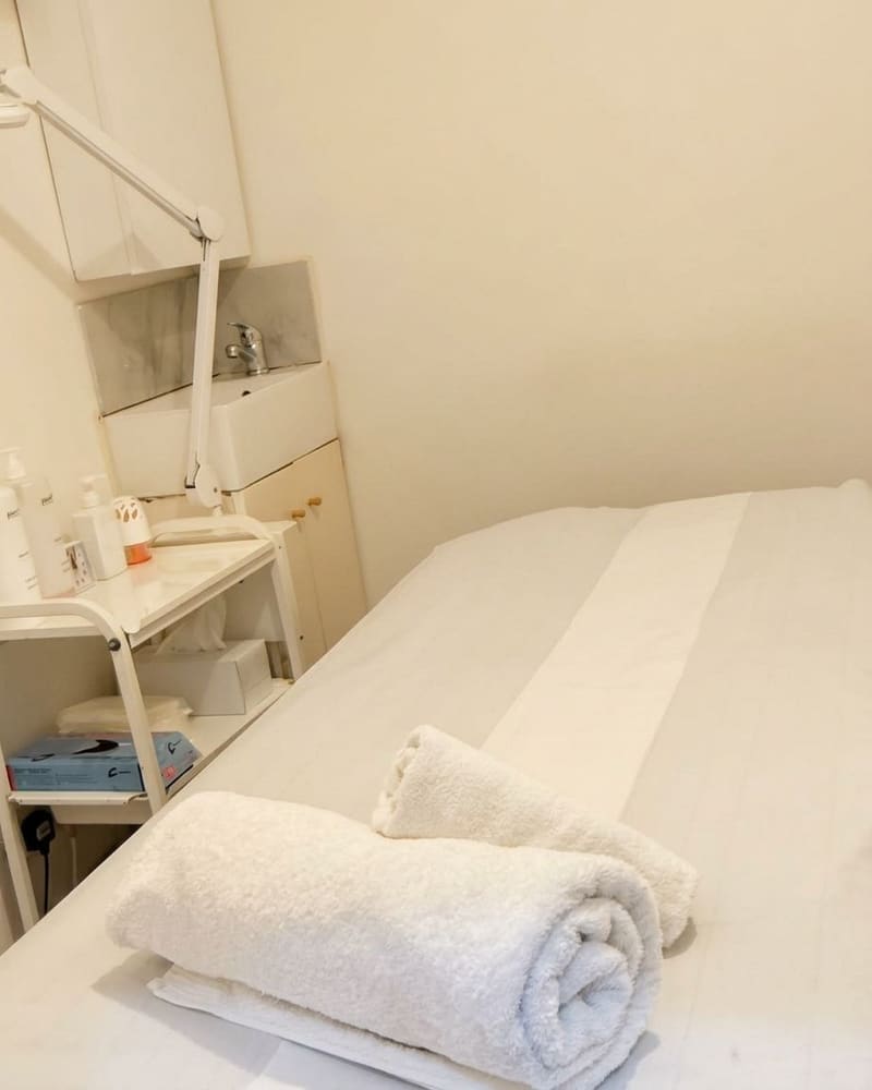 A treatment room at Pure Essentials London with rolled towels on the couch