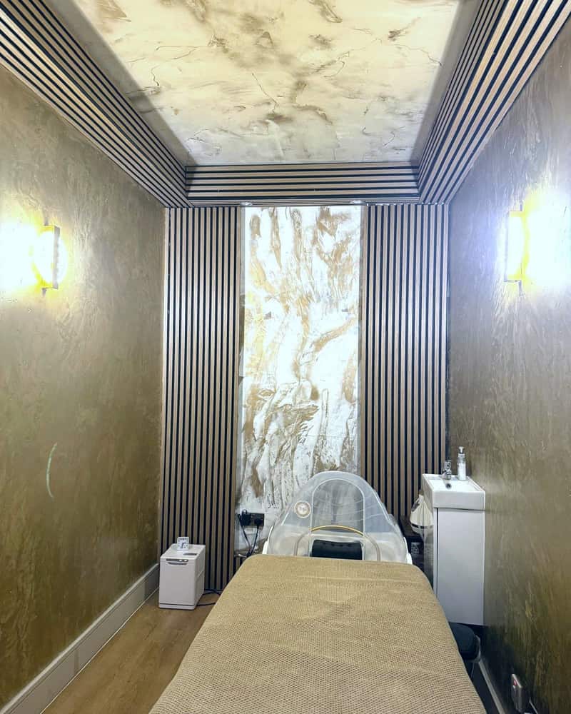 A treatment room at Pure Essentials London with a wood-slat wall and couch